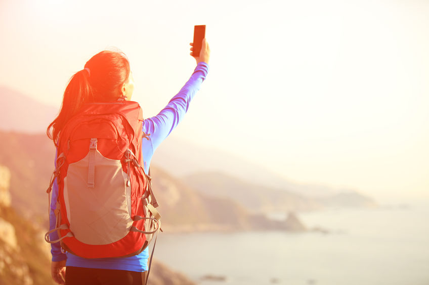 55258766 - woman taking photo with phone at mountain peak