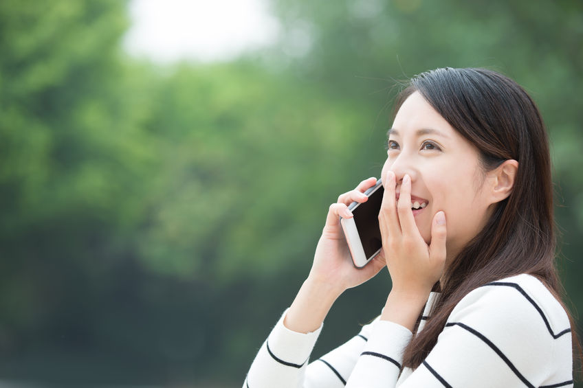 55827168 - happy woman speak and use smart phone outdoor, asian beauty