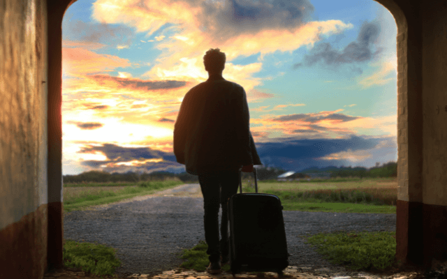 Man with luggage walking through an arch